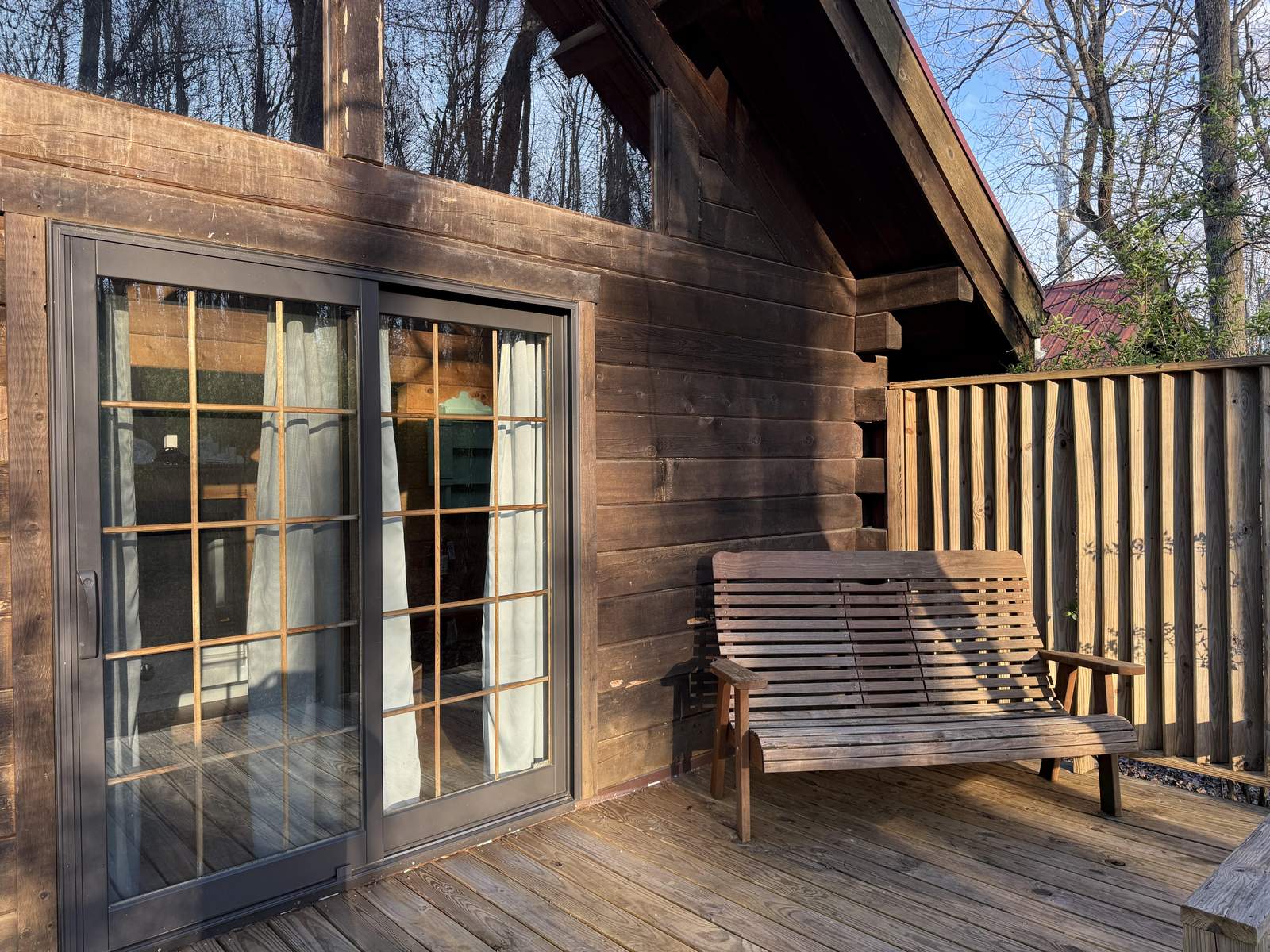 The back porch of a woodland cabin, swing and all.