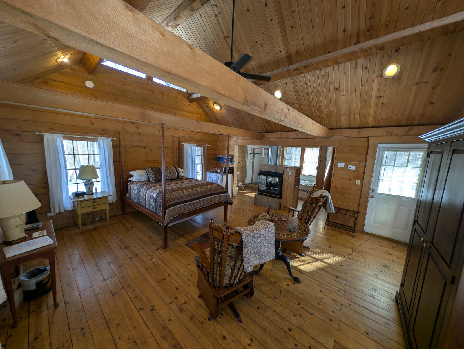 A lofted cabin bedroom with a four-poster bed under open rafters
