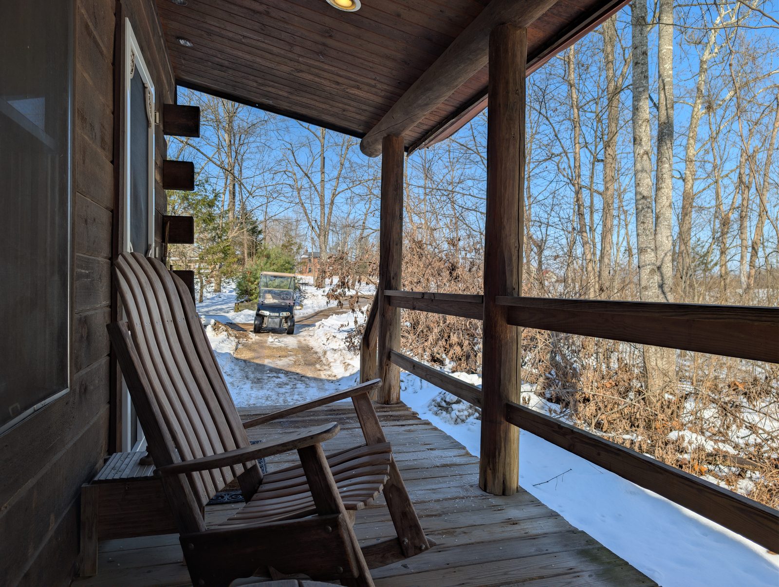 A rocking chair on a cabin porch facing bare winter woods