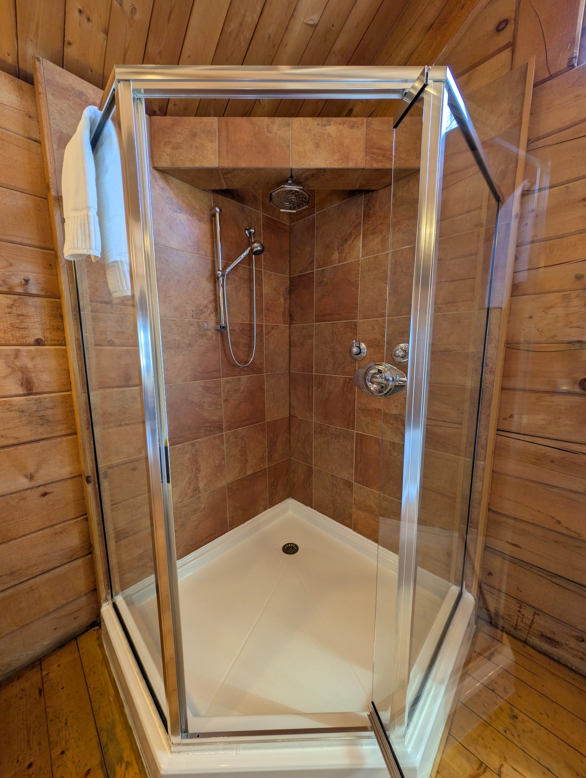 A glass two-person shower in a tiled cabin bathroom
